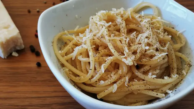 Finished plate of Pasta Cacio e Pepe with pasta, sauce, and garnish.