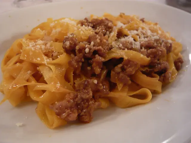 Finished plate of Tagliatelle Bolognese with pasta, sauce, and garnish.